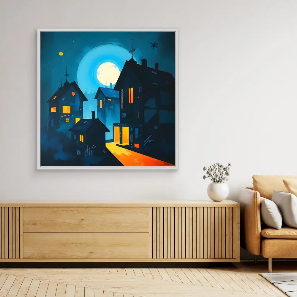 A framed artwork depicting illuminated houses against a moonlit night sky.