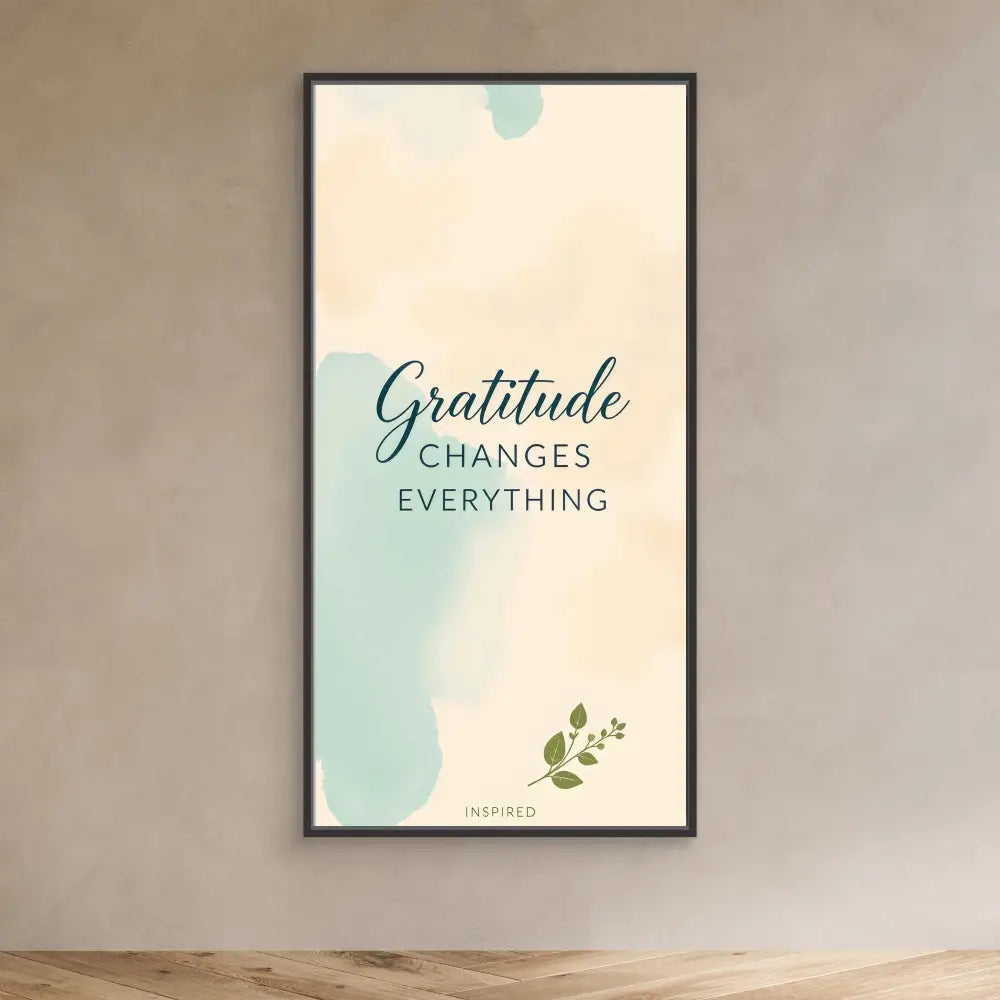 A framed inspirational wall art featuring the text ’Gratitude Changes Everything’ in mint green and cream colors with a small leaf accent.