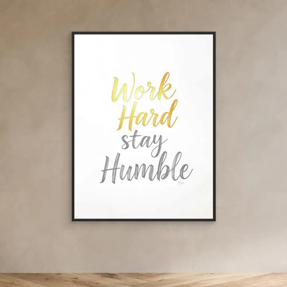 A framed motivational print featuring ’Work Hard Stay Humble’ in gold and gray text.