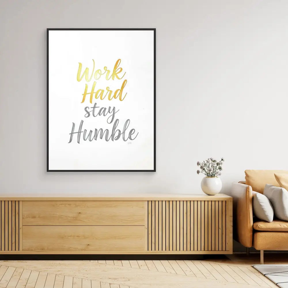 Framed motivational text art displaying ’Work Hard Stay Humble’ in yellow and gray lettering.