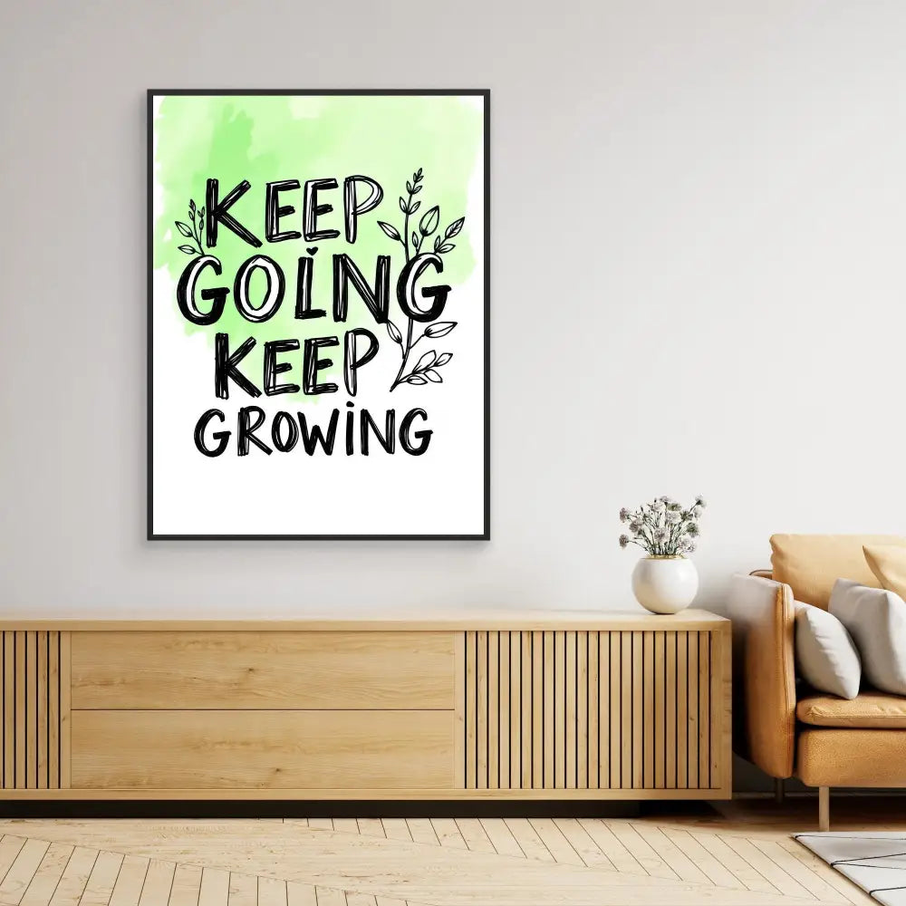 Framed motivational wall art featuring the text ’KEEP GOING KEEP GROWING’ with decorative leaf elements in black and green.