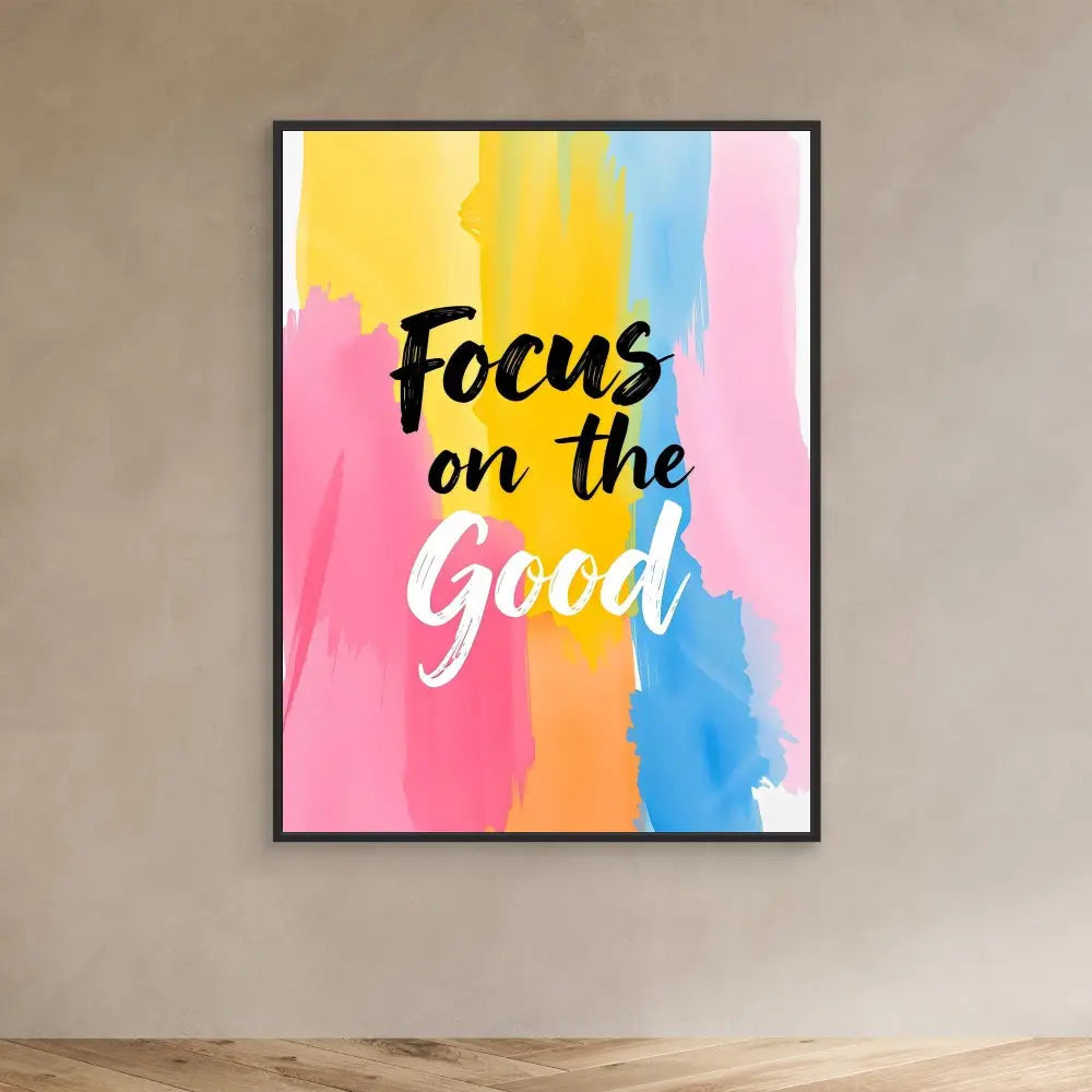 A motivational wall art print featuring ’Focus on the Good’ text over watercolor-style pink, yellow and blue brushstrokes.