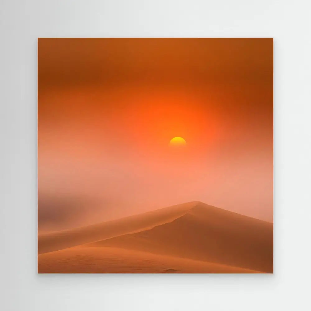 Glowing sun setting behind desert sand dunes in an orange sky.